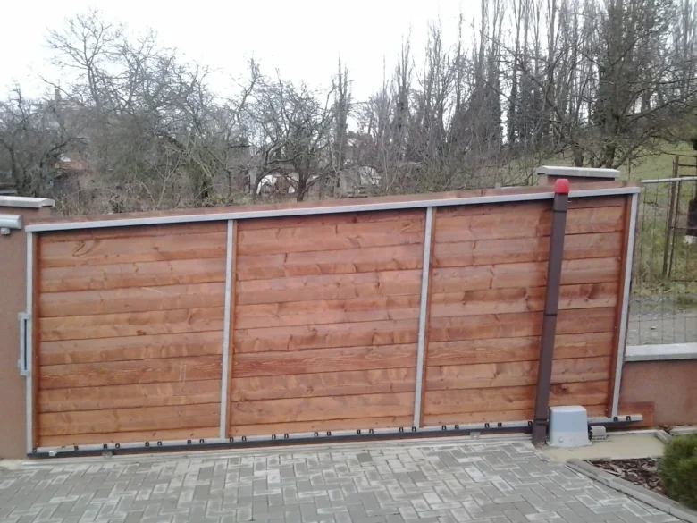 Automatická dřevěná brána se nedokáže zavřít kvůli poruše mechanismu.