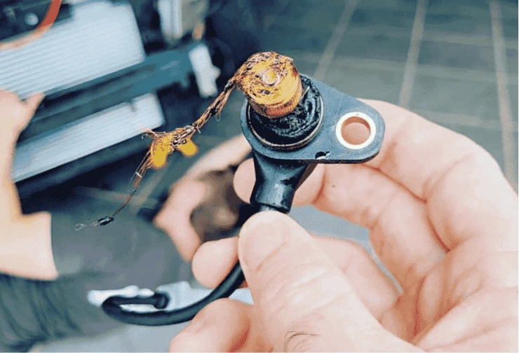 Spálený snímač polohy klikového hřídele v ruce mechanika.