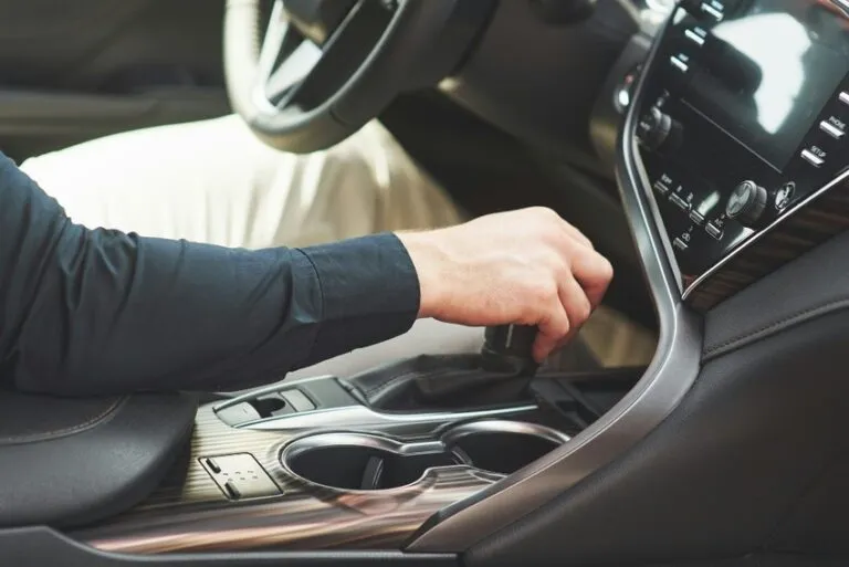 Ruka řidiče mění převod v automobilu na středovém konzolu.