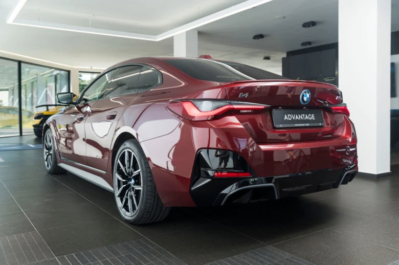 Červený BMW M4 v interiéru prodejny s výrazným zadním difuzorem.