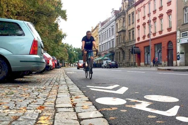 Cyklista jede po vyhrazené cyklosteze v městském prostředí.