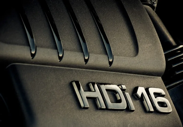 Blízký záběr na kryt motoru s nápisem HDi 16 označujícím technologii Common Rail.