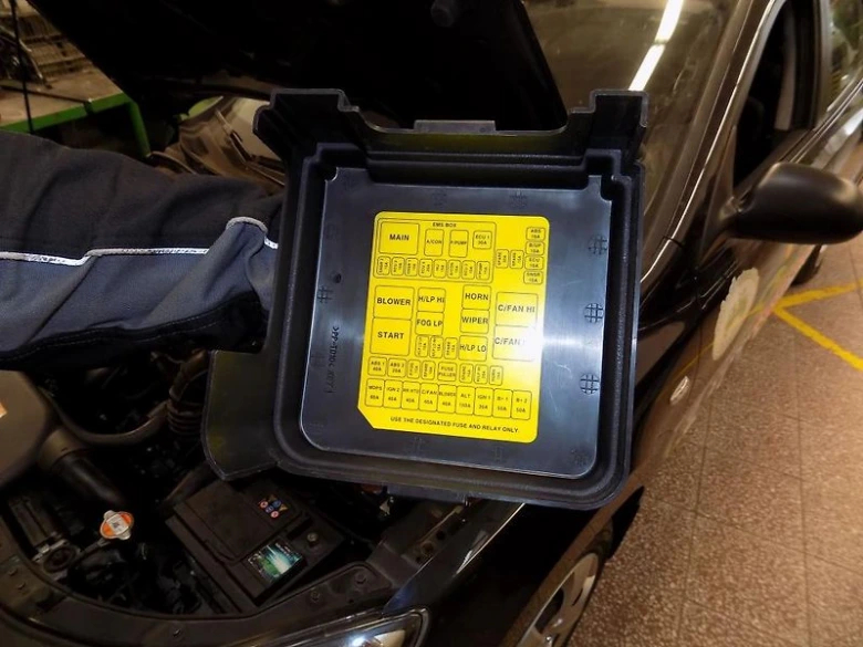 Otevřená pojistková skříň s výkresem v podkapotí automobilu.