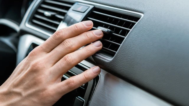 Ruka nastavuje ventilaci v autě pro topení nebo chlazení.