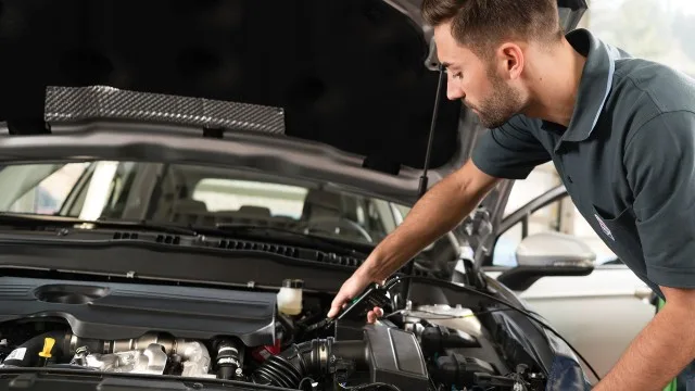 Mechanik kontroluje stav motoru pod otevřenou kapotou.