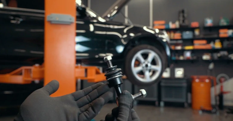 Mechanik drží vzpěru stabilizátoru v dílně pro opravu klepání.