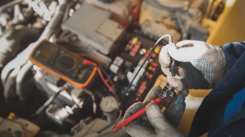 Mechanik měří napětí pro seřízení světlometů autem