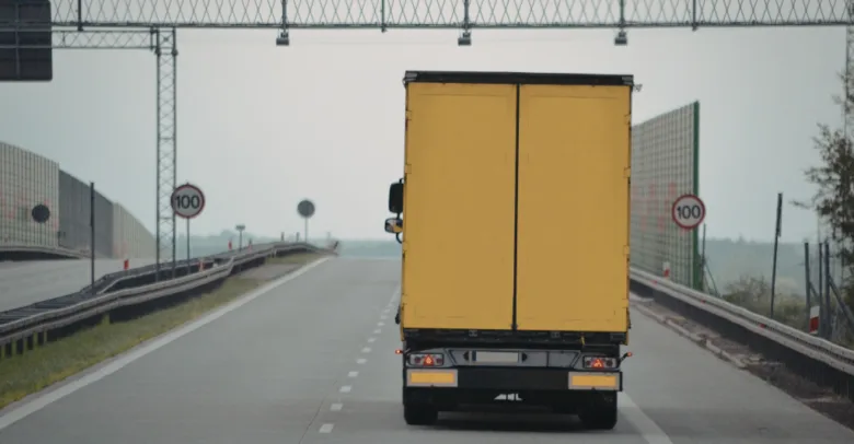 Žlutý nákladní automobil jedoucí dálnicí.