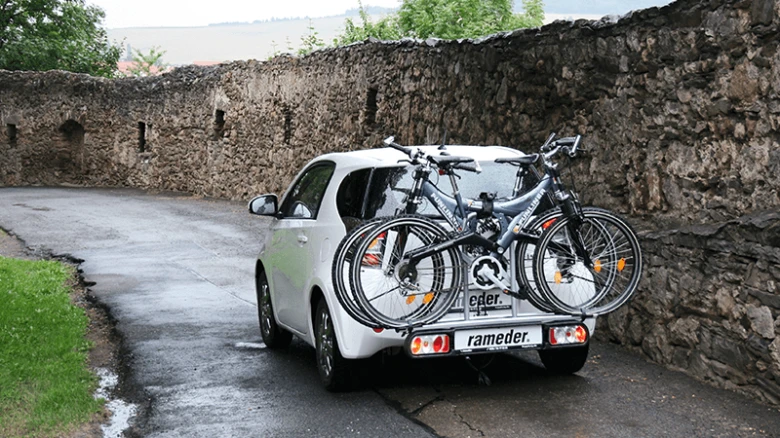 Bílý automobil s tažným zařízením pro dva bicykly.