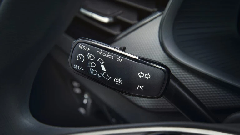Blízký záběr na spínač tempomatu u volantu automobilu.