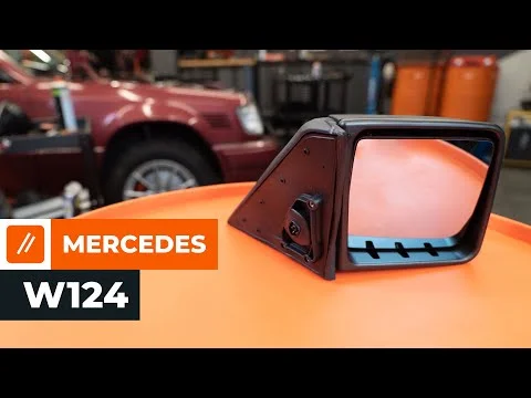 Černé boční zrcátko pro Mercedes W124 na oranžovém povrchu.