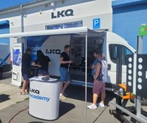 Bílá nákladní vozní služba značky LKQ s lidmi u ní.