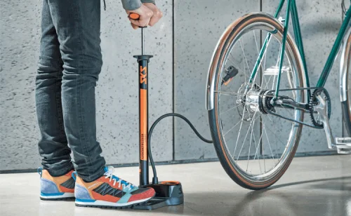 Člověk nafukuje bicyklovaný kolo pomocí stacionárního čerpadla.