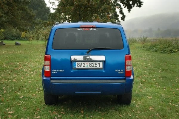 Modrý SUV automobil Dodge Nitro zezadu na trávníku.