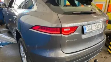Šedý Jaguar F-Pace v servisu s otevřenou kapotou.