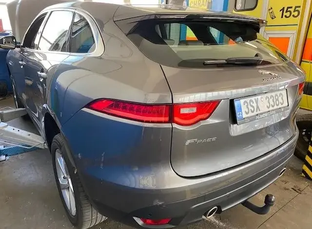 Šedý Jaguar F-Pace v servisu s otevřenou kapotou.