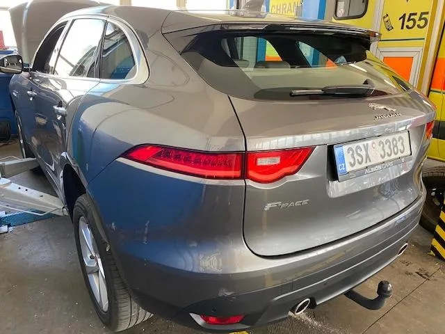 Šedý Jaguar F-Pace v servisu s otevřenou kapotou.