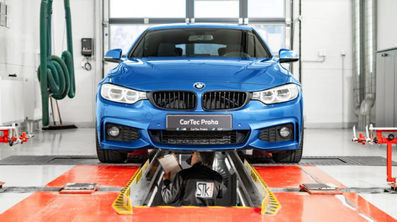 Modrý BMW na zvedáku v dílně pro úpravy vozů.