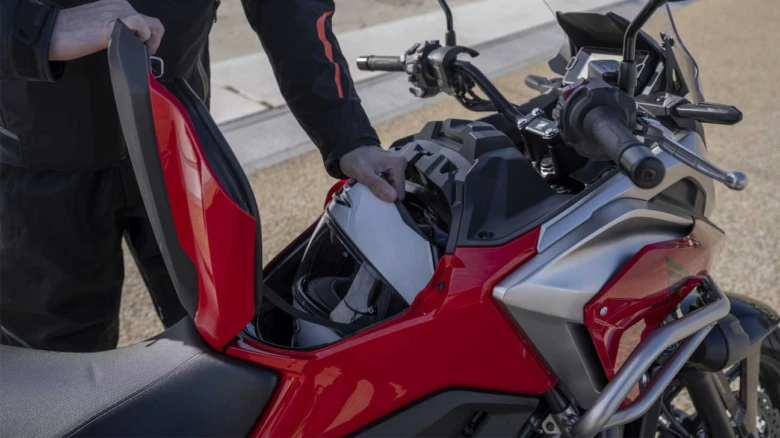 Červená motorka s úložným prostorem pod sedlem na helmy.