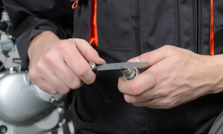 Mechanik měří rozestup elektrod na zapalovací svíčce
