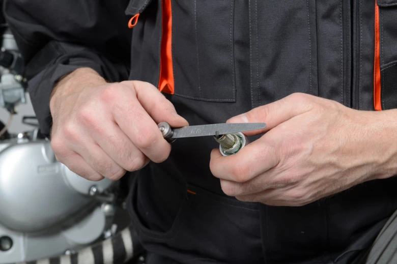 Mechanik měří rozestup elektrod na zapalovací svíčce