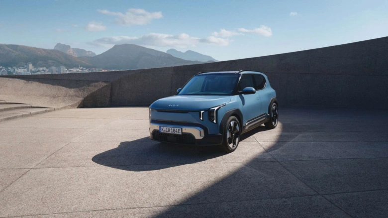 Modrý elektrický SUV Kia EV3 zaparkovaný na terase s horami v pozadí.