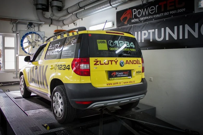 Žlutý vůz na dynometru v dílně pro chiptuning.