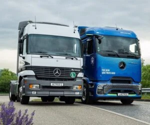 Dva velké nákladní vozy značky Mercedes vedle sebe na silnici.