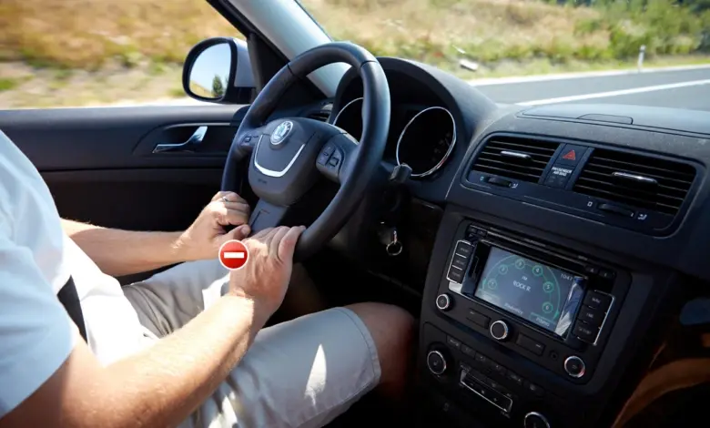 Řidič drží volant oběma rukama při jízdě autem.