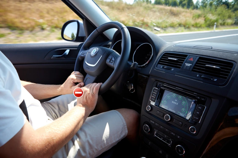 Řidič drží volant oběma rukama při jízdě autem.