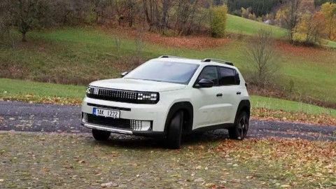 Bílý SUV stojí na silnici v podzimní krajině.